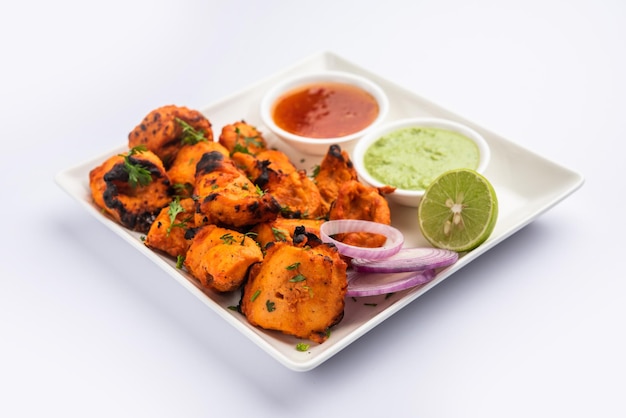 Indian chicken tikka kebabs, marinated in spices and yogurt and roasted in tandoor. served with green chutney and onion. selective focus