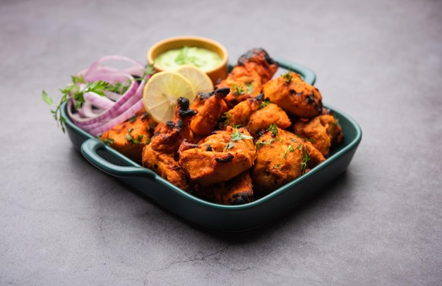 Indian chicken tikka kebabs, marinated in spices and yogurt and roasted in tandoor. served with green chutney and onion. selective focus