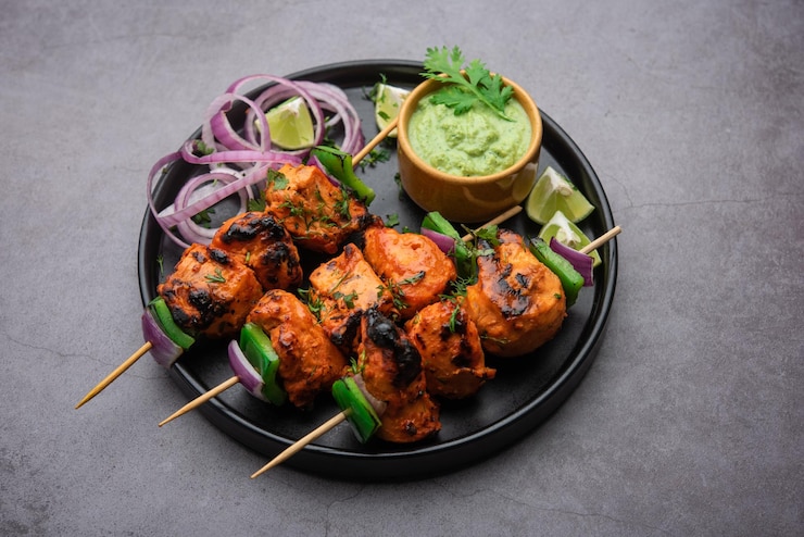 Photo indian chicken tikka kebabs, marinated in spices and yogurt and roasted in tandoor. served with green chutney and onion. selective focus