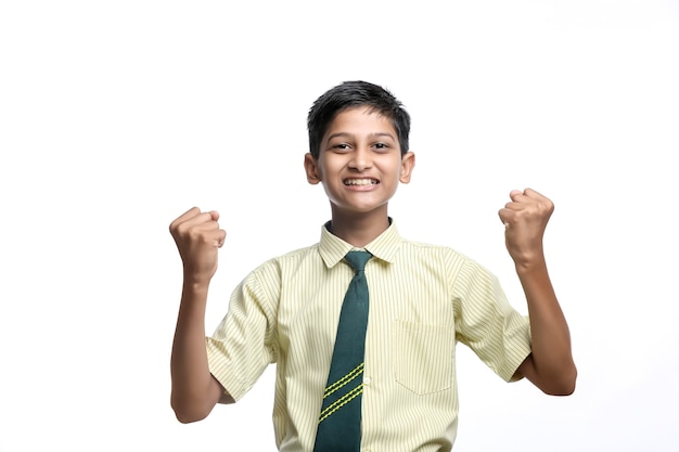 Indian child giving winning gesture on white background.