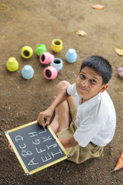 Indian child writing A B C D alphabet on Chalkboard