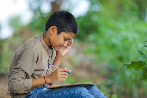 Индийский ребенок, пишущий в записной книжке