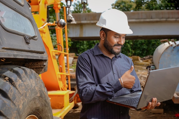 Indian civil engineer working in building construction site with crane construction