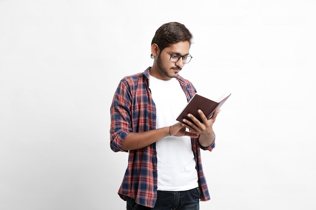 Indian college student reading book on white wall