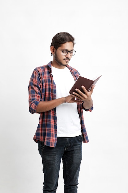 Indian college student reading book on white wall