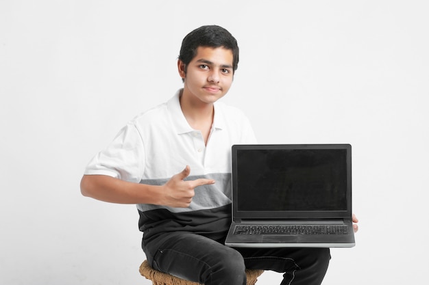 Indian college student showing laptop screen on white wall