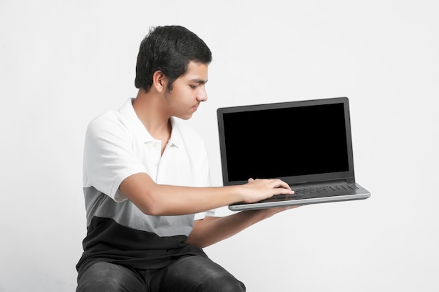 Indian college student showing laptop screen on white wall