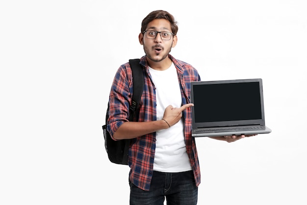 Indian college student showing laptop screen on white wall