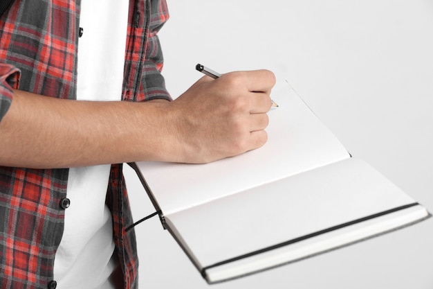 Indian college student writing some notes in notebook on white wall