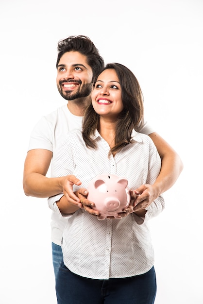 Indian couple with piggy bank standing isolated over white background