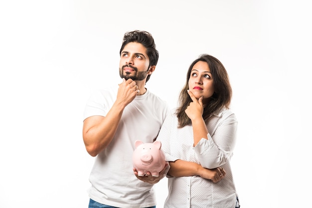 Indian couple with piggy bank standing isolated over white background