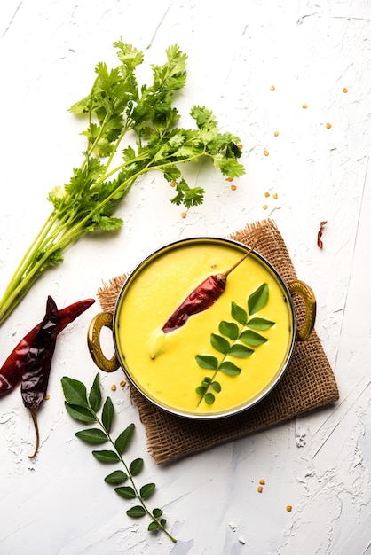 Indian Cuisine Kadhi - Vegetarian Curry Made of Buttermilk And Chick Pea Flour. served in a bowl or Karahi over moody background, selective focus