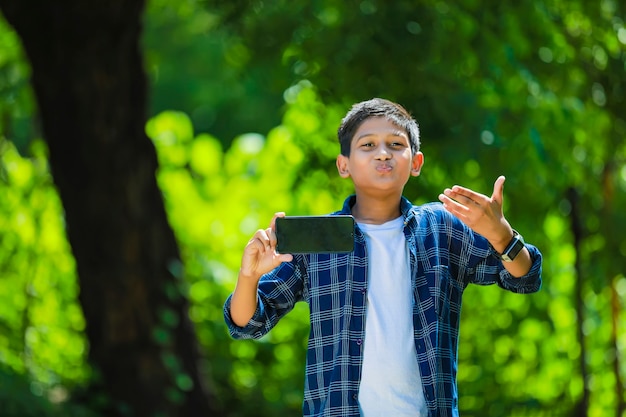 Bambino sveglio indiano che mostra smartphone