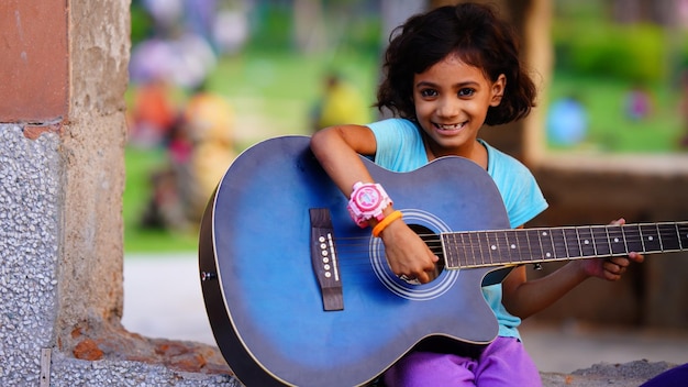 Indian cute girl with blue guitar in park