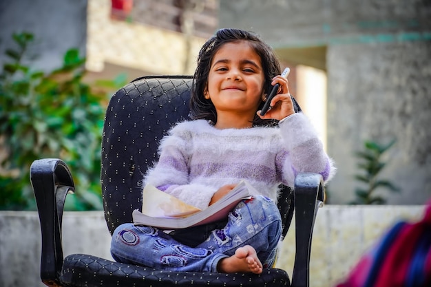 Indian cute little girl talk on phone with cute smile on face