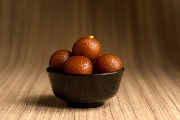 Indian Dessert of Sweet Dish: Gulab Jamun in kom op houten achtergrond.