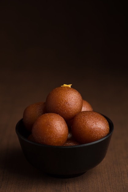 Indian dessert or sweet dish Gulab jamun in a bowl on wooden.