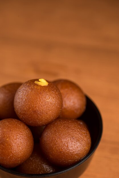 Indian dessert or sweet dish gulab jamun in a bowl on wooden