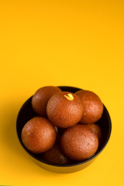 인도 디저트 또는 달콤한 요리 : 노란색 배경에 그릇에 Gulab Jamun.