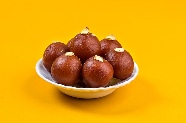 インドのデザートまたはスウィートディッシュ：黄色の白いボウルにGulab Jamun