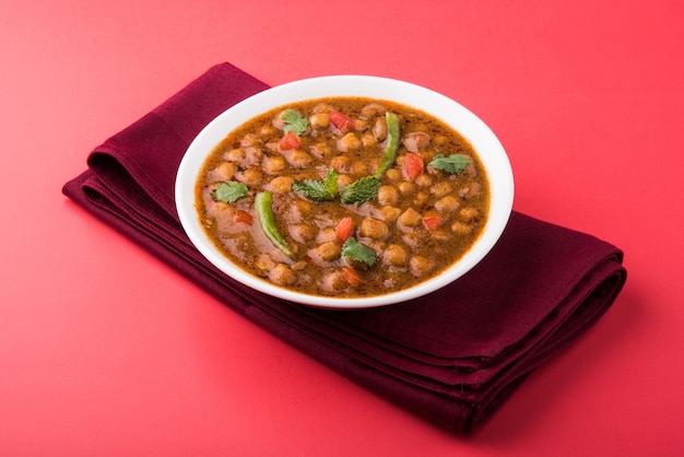 インド料理のスパイシーなひよこ豆のカレーは、チョーラまたはチャナマサラまたは一般的にはチョーレーとしても知られ、カラフルなまたは木製の背景の上に揚げたプリまたはプーリを添えて提供されます。セレクティブフォーカス