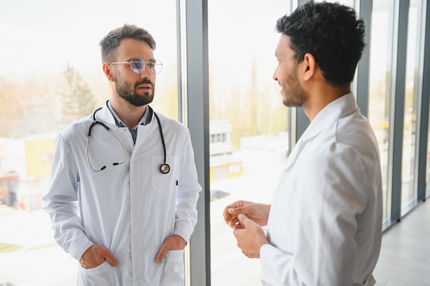 An Indian doctor and a European doctor stand together in a hospital lobby