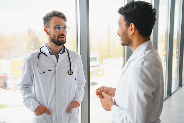 Photo an indian doctor and a european doctor stand together in a hospital lobby