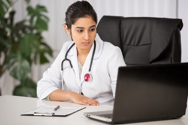 Indian doctor wearing a white coat in white clinic.