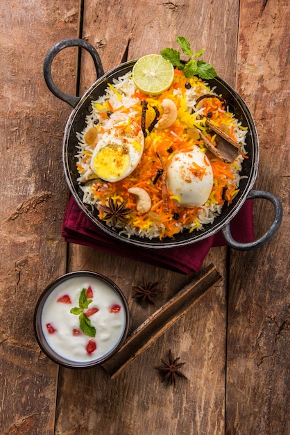 Indian Egg Biryani or anda rice served in kadhai or kadai with yogurt dip, selective focus