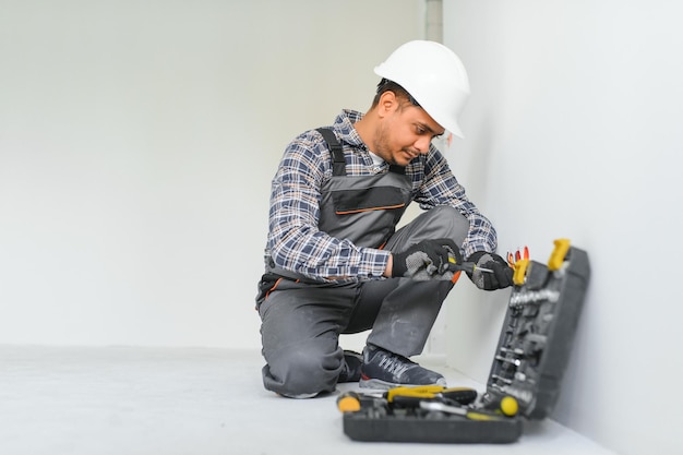 an Indian electrician installs an outlet in a new building