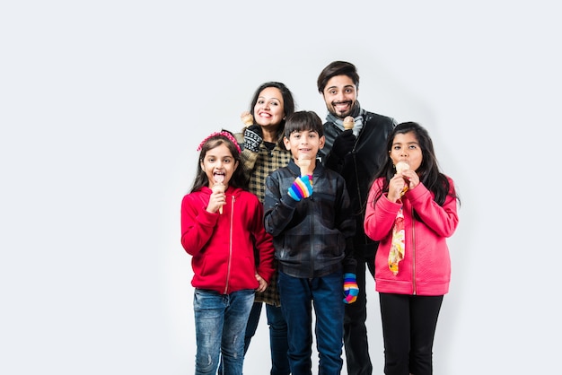 Indian family eating ice cream in warm clothes on white background