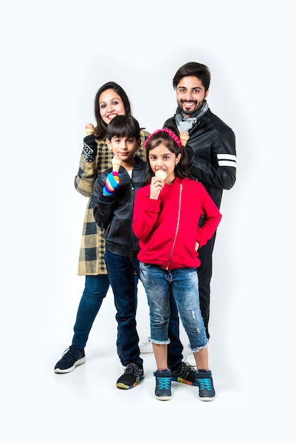 Indian family eating ice cream in warm clothes on white background