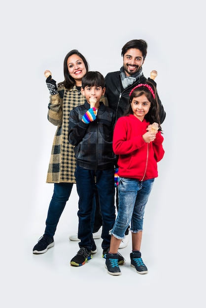 Indian family eating ice cream in warm clothes on white background