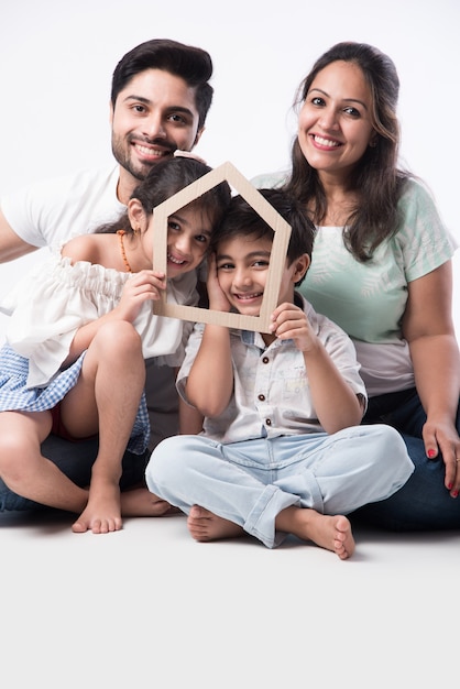 インドの家族家の3Dペーパーモデルを保持している父、母、息子、娘-インドのリアルIstateコンセプト