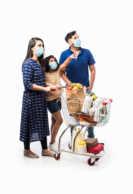 Indian family shopping con i bambini durante l'epidemia di virus. madre, padre e figlia che indossano una maschera chirurgica per l'acquisto di generi alimentari al supermercato. famiglia in negozio.