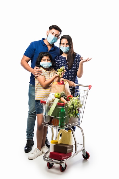 Indian Family Shopping with kids during virus outbreak. Mother, father and daughter wearing surgical face mask buying groceryÂ in supermarket. Family in shop.