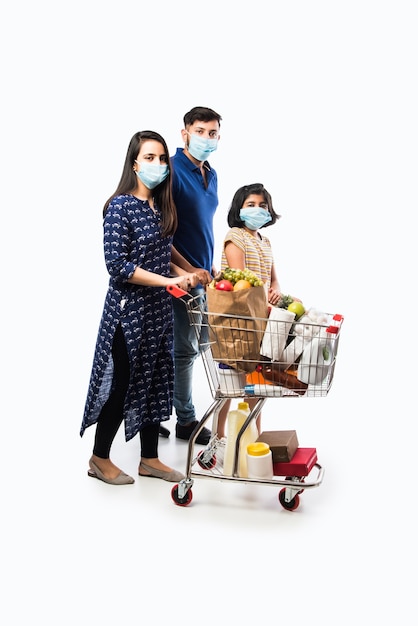 Indian Family Shopping with kids during virus outbreak. Mother, father and daughter wearing surgical face mask buying groceryÂ in supermarket. Family in shop.