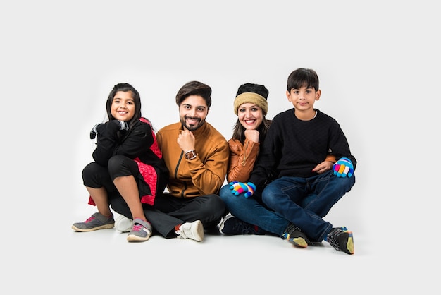 Indian family in warm clothes sitting against white background. Ready for winter