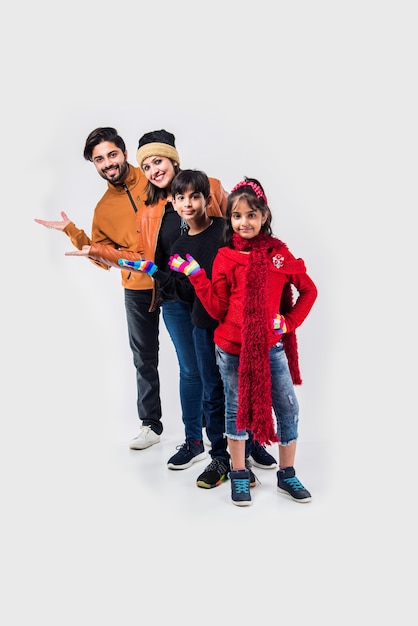 Indian family in warm clothes standing against white background. Ready for winter