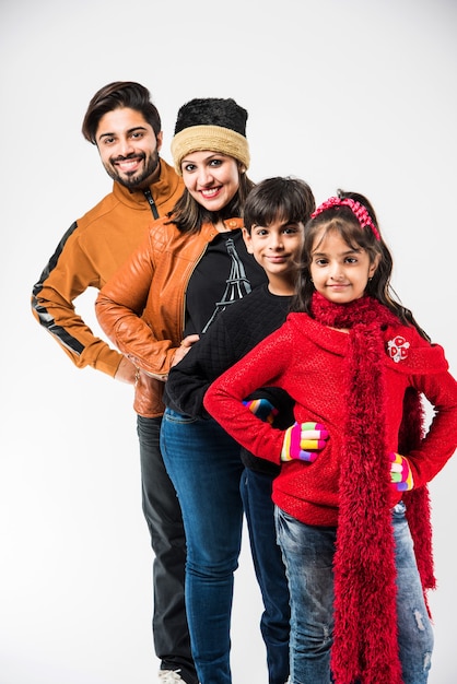 Indian family in warm clothes standing against white background. Ready for winter