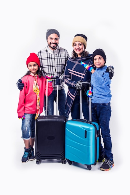 Indian family with suitcase while wearing warm cloths, ready for winter holidays