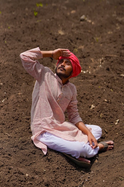Индийский фермер на поле сельского хозяйства и глядя на небо, ожидая дождя.