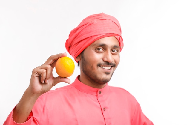 Indian farmer holding an orange fruit in hand over white background.