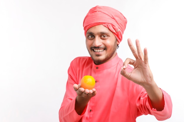 Photo indian farmer holding an orange fruit in hand over white background.