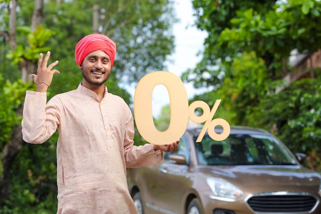 Indian farmer holding zero percent sign board and standing with new car