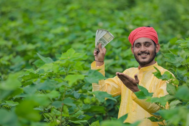 Indian farmer showing money at cotton field