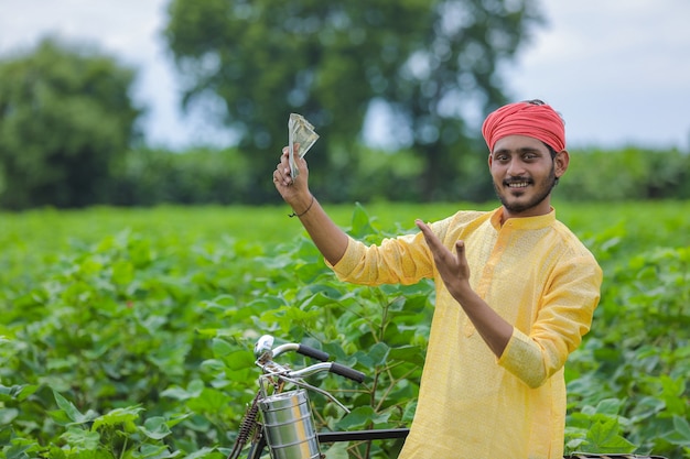 Indian farmer showing money at cotton field