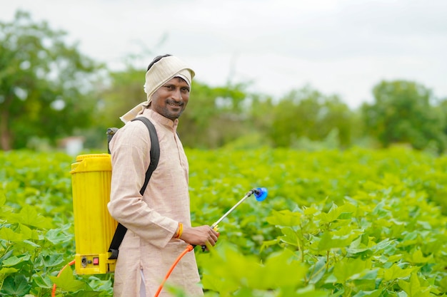 Indian farmer spraying pesticide at cotton field.