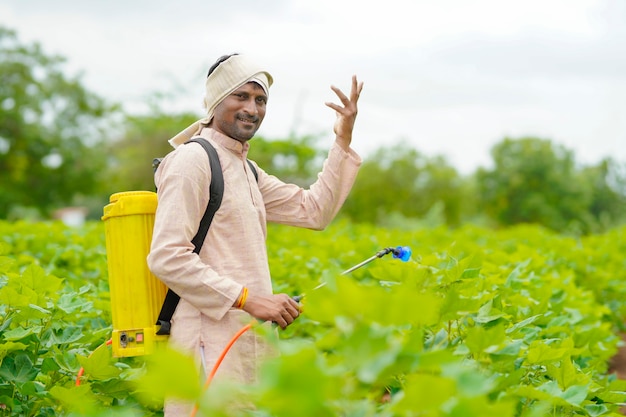 Indian farmer spraying pesticide at cotton field.