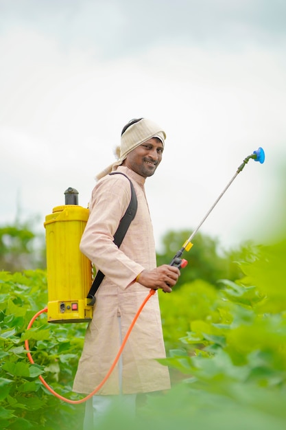 Indian farmer spraying pesticide at cotton field.